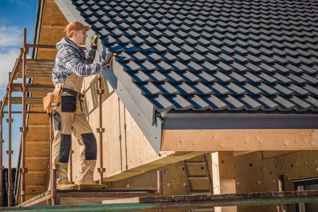 Professional Roofer Worker Finishing Ceramic Roof Tiles Installation. Smiling and Happy Worker on a Scaffolding.
